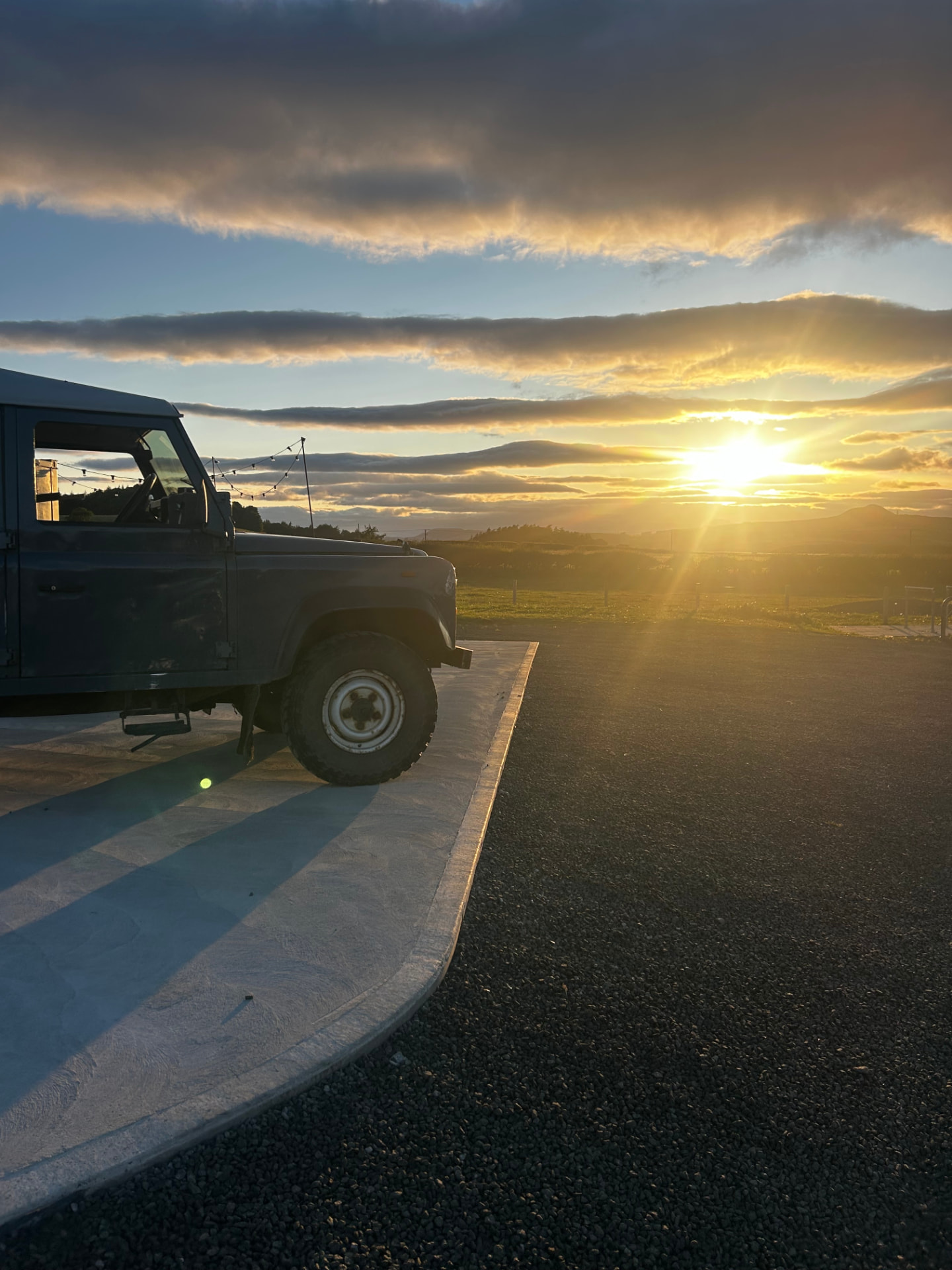 A Land Rover parked at the café at sunset, looking out over the fields
