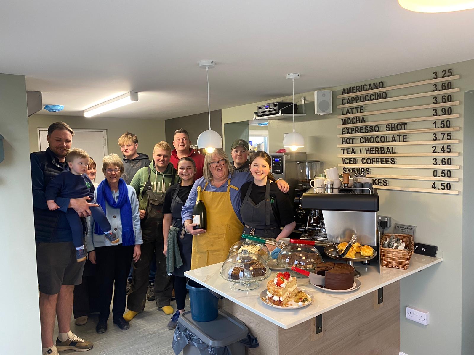 The Starscape family and team standing behind the café counter with cakes on it